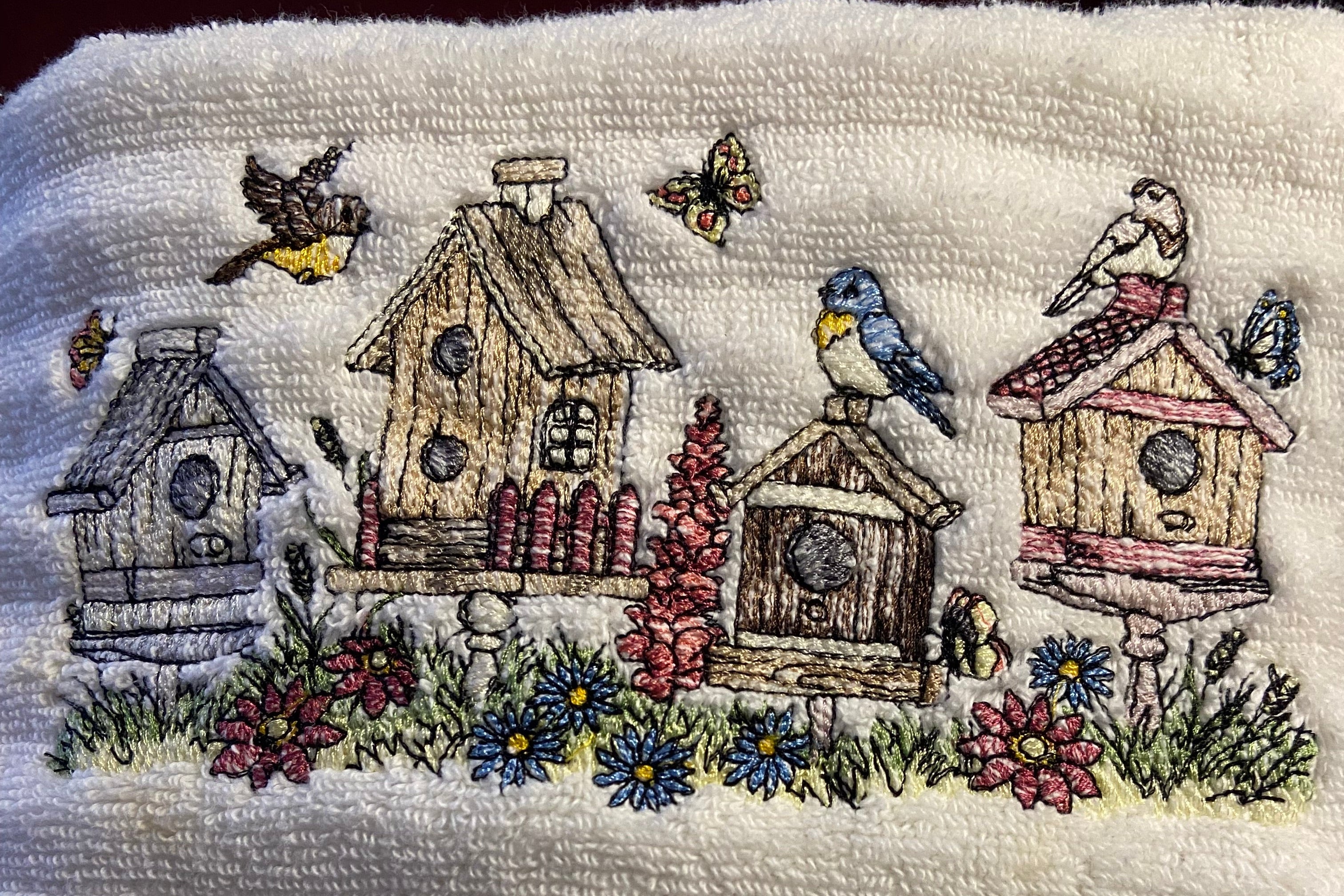 Embroidered design of birdhouses and flowers on a textured fabric background