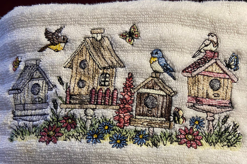 Embroidered design of birdhouses and flowers on a textured fabric background